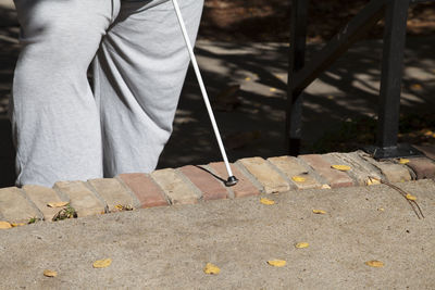 Midsection of blind person with stick in sunny day