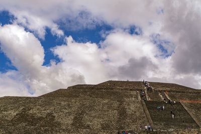 Low angle view of people on mountain against sky