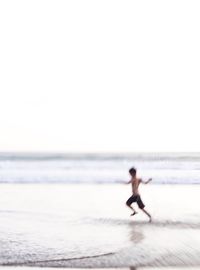 People enjoying on beach against clear sky