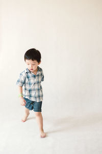 Full length of cute boy standing against white background
