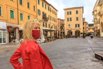 Portrait of woman standing on footpath in city