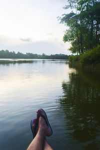 Low section of person in lake against sky