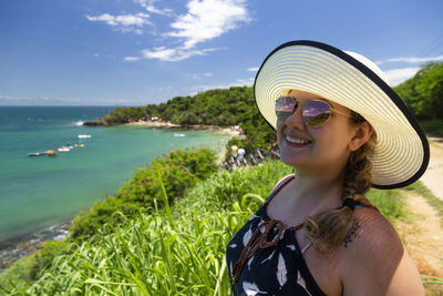 Portrait of smiling young woman in sunglasses against sky