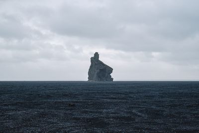 Built structure on rocks by sea against sky