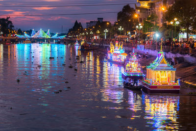 Illuminated buildings by river in city at night soc trang