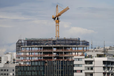 Crane by building against sky