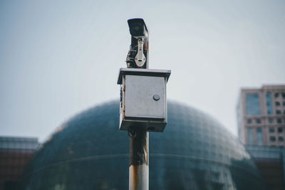 Low angle view of security camera against sky