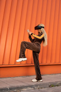 Pretty african american woman using virtual reality glasses on an orange background