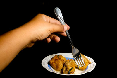 Midsection of person holding ice cream against black background