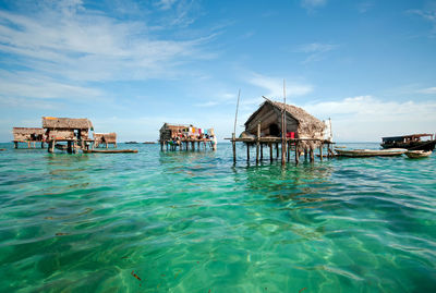 Stilt house in sea against sky