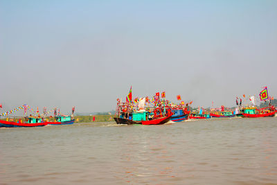 Boats sailing in sea against clear sky