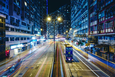 Light trails on road amidst buildings in city at night