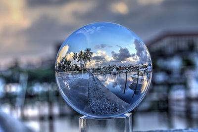 Close-up of crystal ball on glass against sky