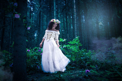Woman wearing white dress while standing in forest