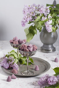 Belgian sweets cuberdon and pralines in silver glasses, spring still life with lilac flowers