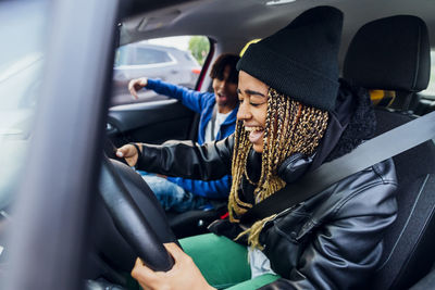 Cheerful woman sitting in car enjoying with friend