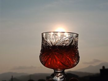 Close-up of beer glass against sky during sunset