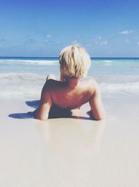 Woman lying on beach against sky