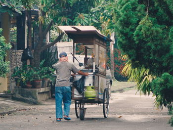 Rear view of man walking on street amidst buildings