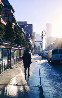 Rear view of man walking on street in city