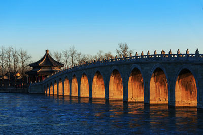 Arch bridge over river against clear sky