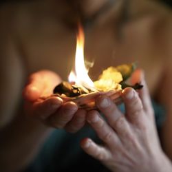 Close-up of hand holding burning candles