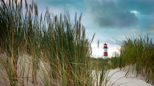 Lighthouse by sea against sky