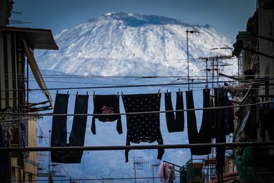 Low angle view of flags hanging on snow covered mountain against sky