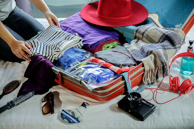 Midsection of woman packing suitcase on bed at home