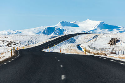 Road amidst snowcapped mountains against sky