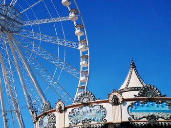 Low angle view of ferris wheel against clear blue sky