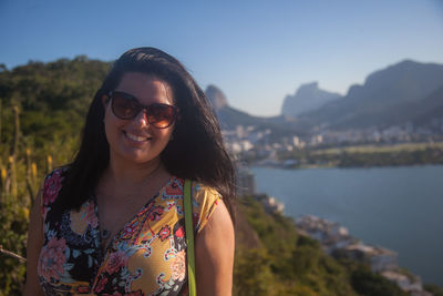 Portrait of young woman wearing sunglasses against sky