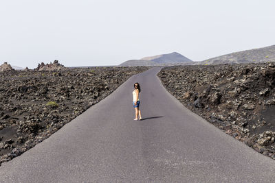 Rear view of woman on road against clear sky