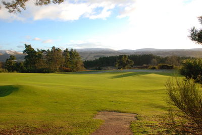 Scenic view of golf course against sky