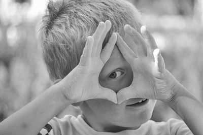 Close-up portrait of boy covering face with hand