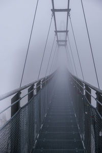 Low angle view of bridge against a wall of fog