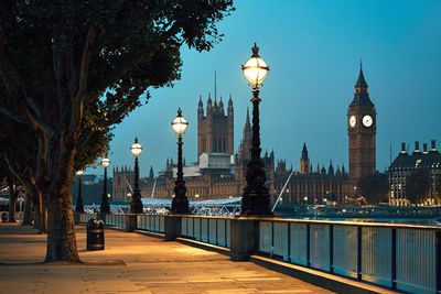 Illuminated big ben and buckingham palace against clear sky at dusk