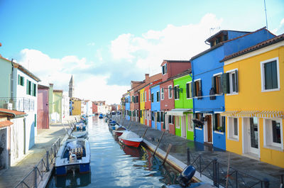 Boats in canal amidst buildings in city against sky