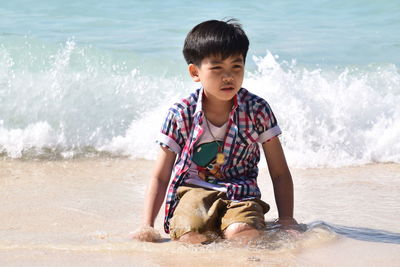 Boy kneeling on sand at beach