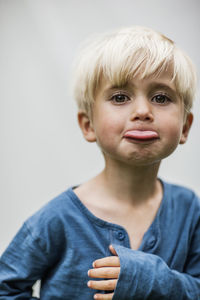 Portrait of boy sticking out tongue, studio shot