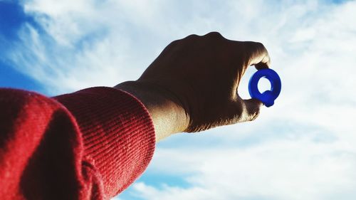 Cropped image of hand holding letter q against sky