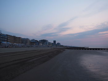 City by sea against sky at sunset