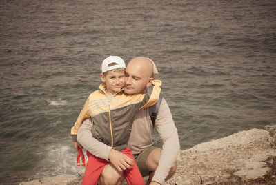 Portrait of smiling son with father by sea