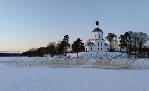 Church by building against clear sky during winter