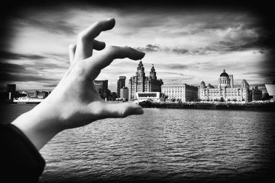 Midsection of man and river against buildings in city