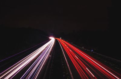 Light trails on road against sky at night