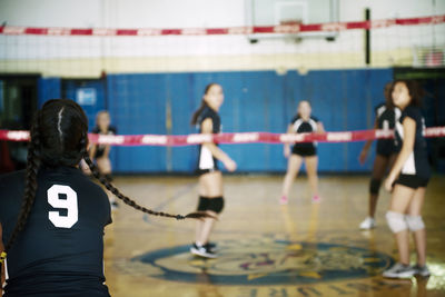 Rear view of girl playing volleyball in court