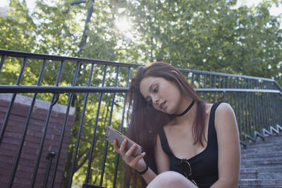 A young woman on a staircase looking at her smart phone