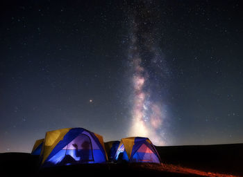 Illuminated tents against sky at night