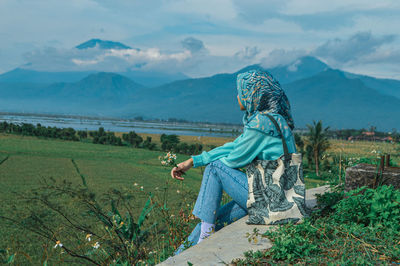 Rear view of boy on field against sky